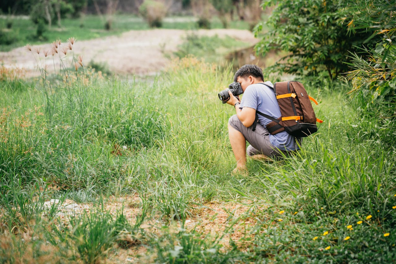 our-experience Photographer crouches in lush greenery to capture the beauty of nature.
